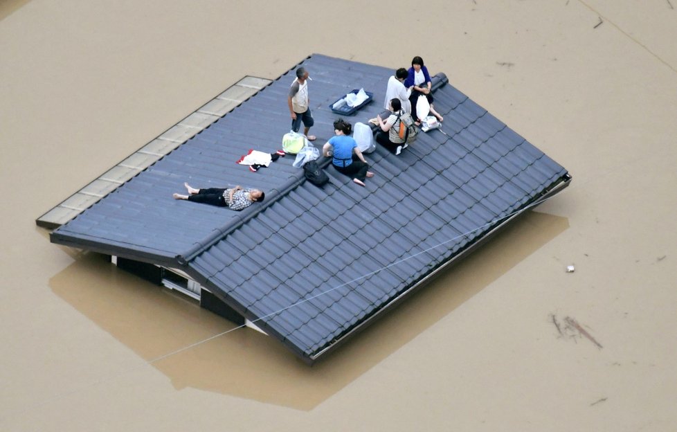 Lidé ve městě Kurashiki na jihozápadě Japonska čekají při záplavách na střeše na záchranu.