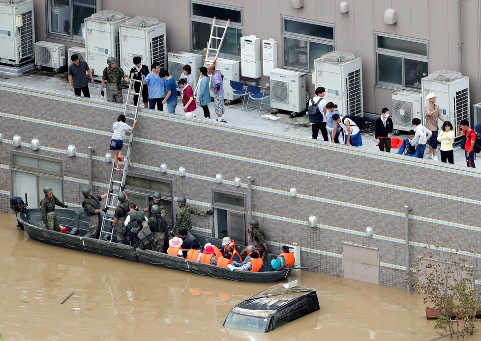 Několik lidí záplavy ve městě Kurashiki uvěznily na střeše nemocnice. Japonští záchranáři pro ně přijeli na člunech.