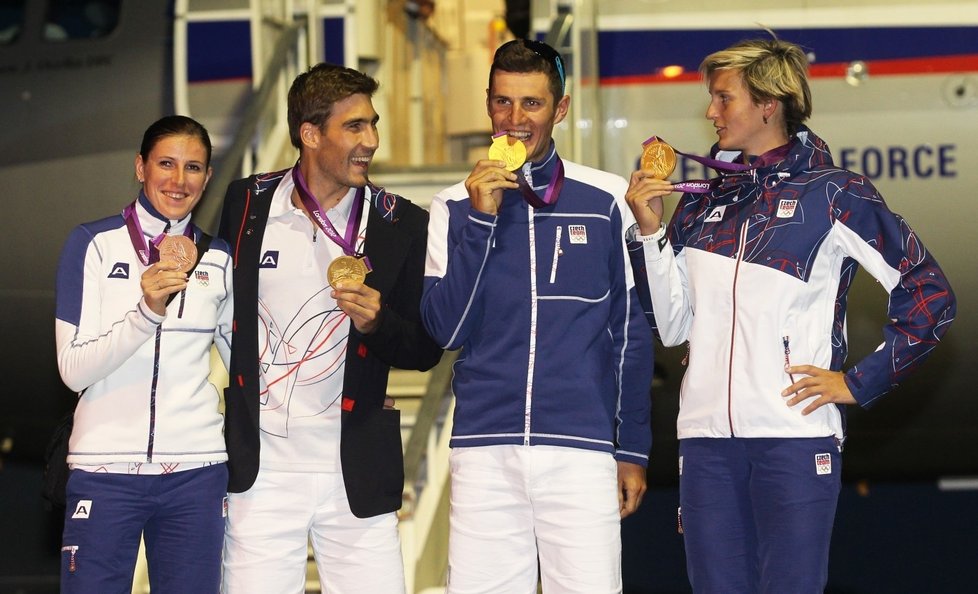 Další zlatí olympionici - David Svoboda a Barbora Špotáková - po příjezdu zpátky do ČR přihlížejí, jako Jaroslav Svoboda ochutnává medaili.