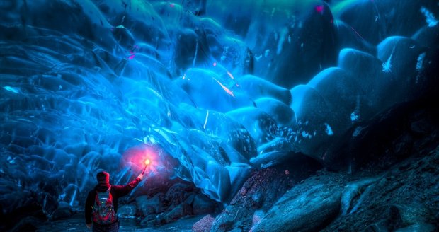 Přítel Rona drží červenou světlici uvnitř jeskyně.