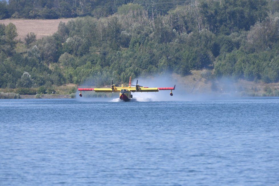 Do boje s lesním požárem v Národní parku České Švýcarsko se zapojila dvojice hasičských letadel z Itálie. Vodu nabírají v jezeře Milada. (28. července 2022)