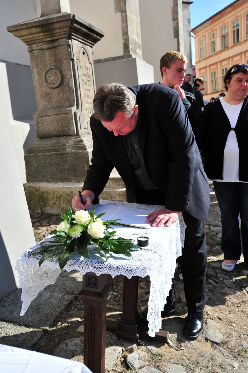 Lidé se před kostelem zapisují do kondolenční knihy