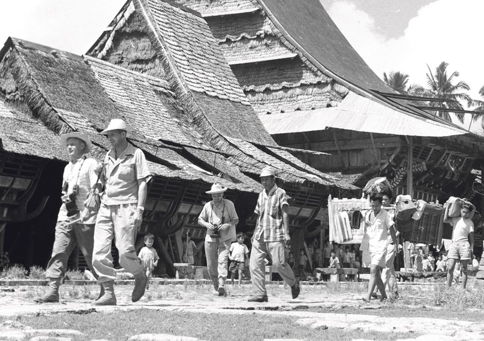 (Indonésie, ostrov Nias, 1962) V čele kráčí Hanzelka, Zikmund a jejich štáb, v pozadí stojí 900 let starý královský dům.
