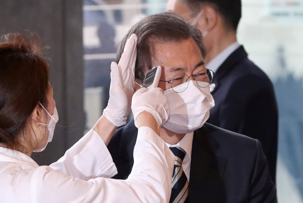Pracovnice měří tělesnou teplotu jihokorejského prezidenta Moon Jae po příletu do Seoulu