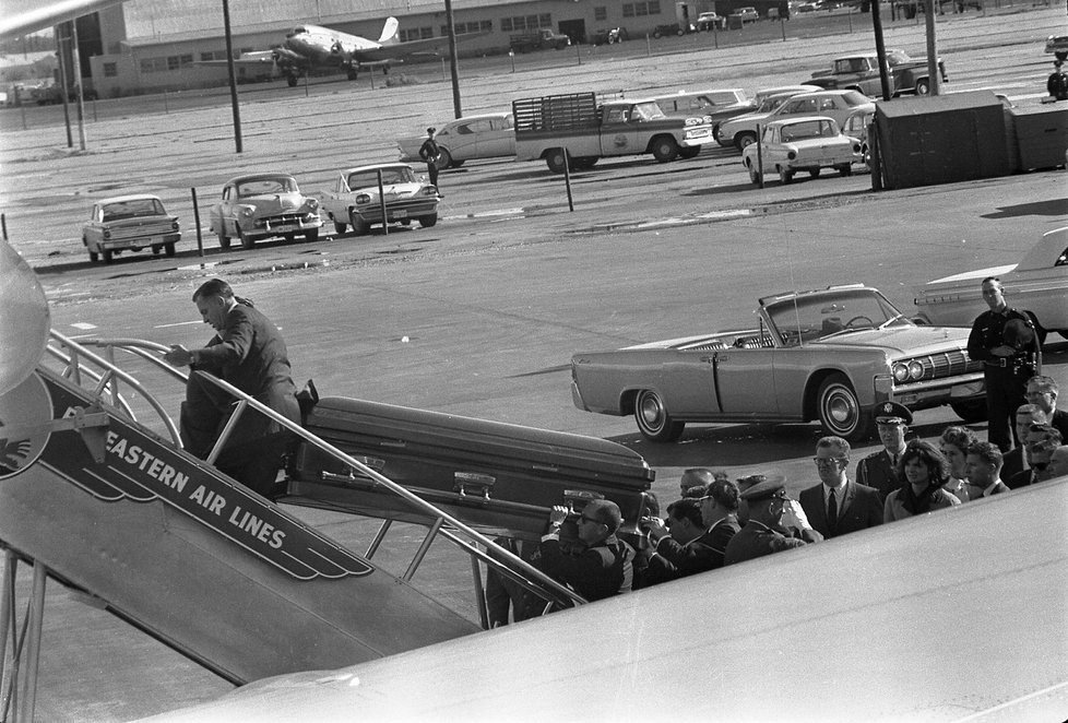 Rakev se zavražděným prezidentem je vynášena do letadla Air Force One.