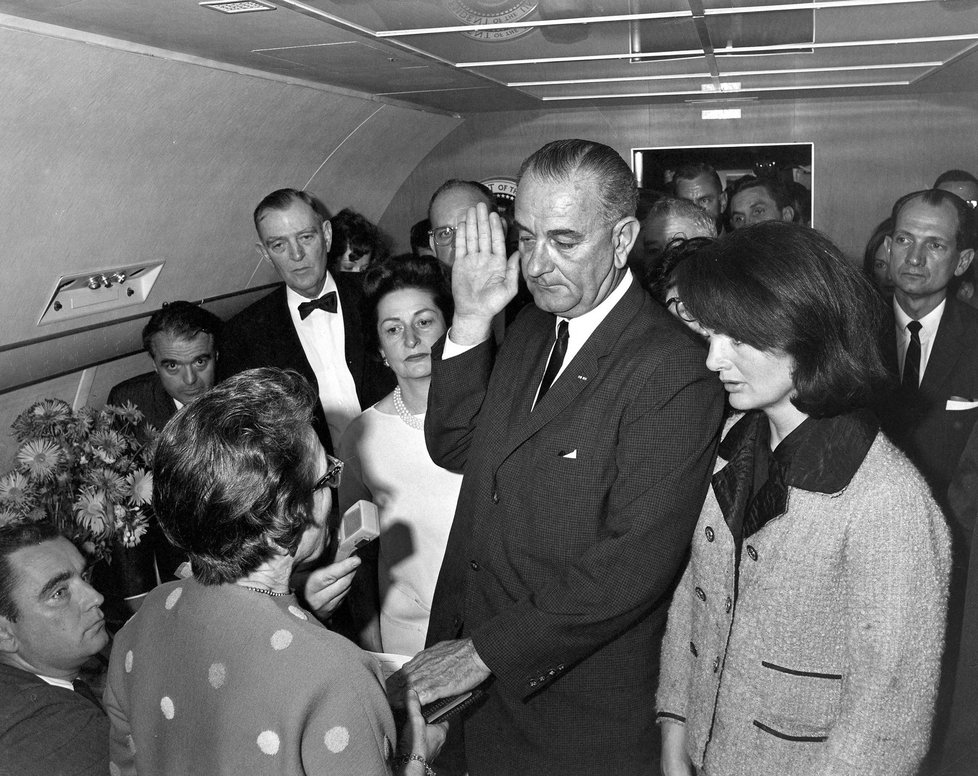 Lyndon B. Johnson skládá prezidentskou přísahu na palubě Air Force One 22. listopadu 1963 poté, co byl v Dallasu zavražděn prezident John F. Kennedy.