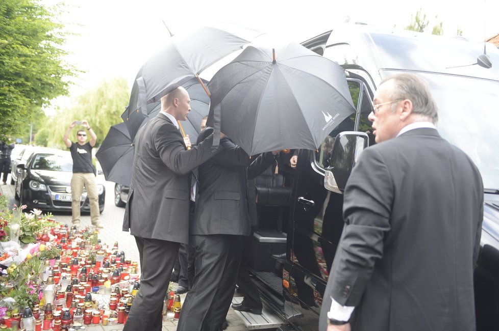 Josef Rychtář vystupuje z dodávky. Ochranka ho stále chrání deštníkama.