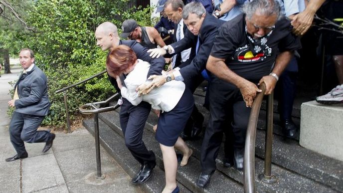 Julia Gillardová si s pomocí své ochranky razí cestu skrze dav protestujících