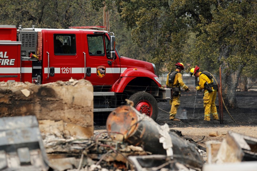 Hasiči u ohořelých základů spáleného domu západně od Reddingu v Kalifornii.