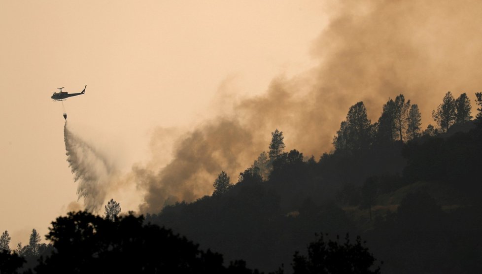 Helikoptéra hasičů hasí lesní požár západně od Reddingu v Kalifornii.