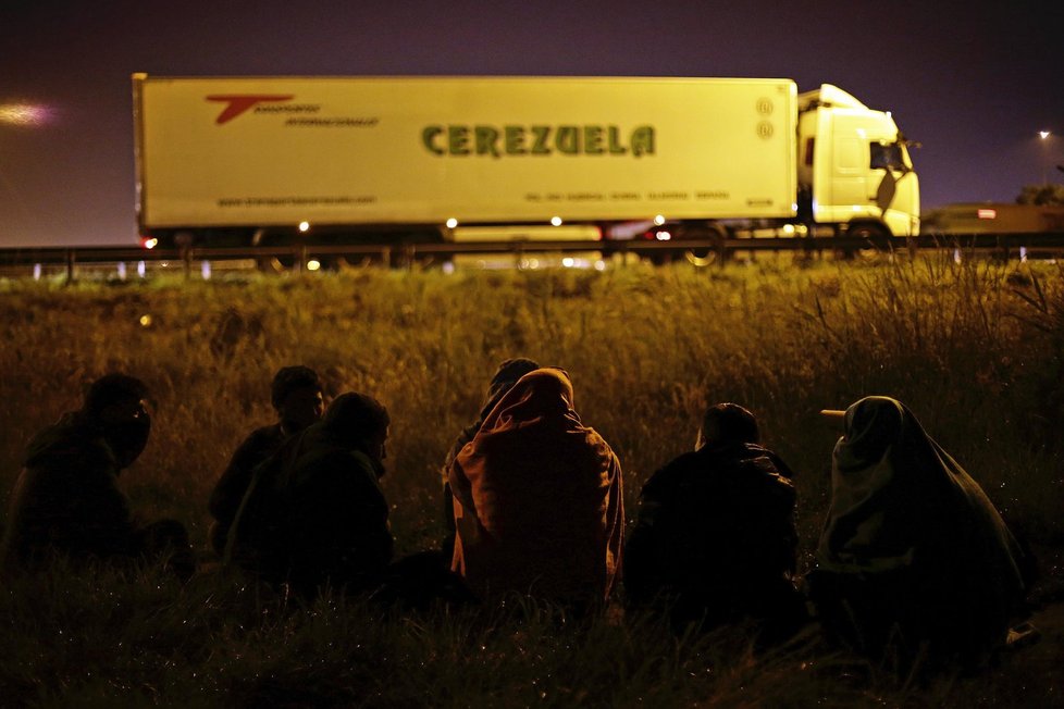 Uprchlíci ukrytí pod rouškou tmy čekají na okamžik, kdy se vrhnou na kamion.