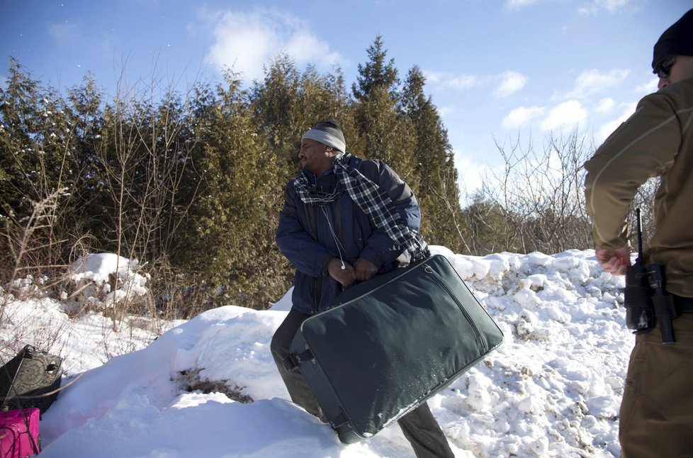 Kontrolovaný muž (údajně původem z Súdánu) hází zavazadla své rodiny směrem ke kanadské hranici.