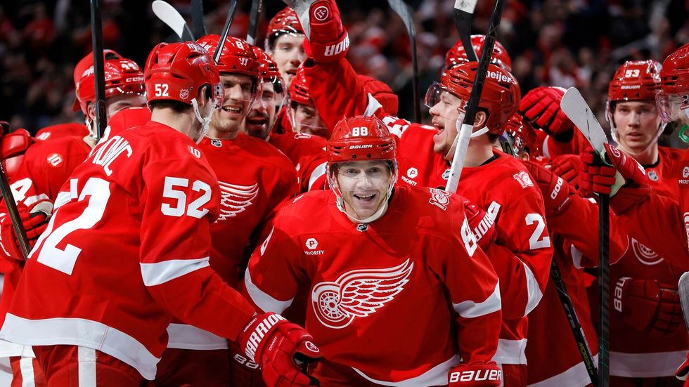 Patrick Kane je obklopen spoluhráči poté, co zaznamenal svůj 1375. bod, čímž překonal Mikea Modana a jeho rekord NHL v počtu bodů hráče narozeného v USA