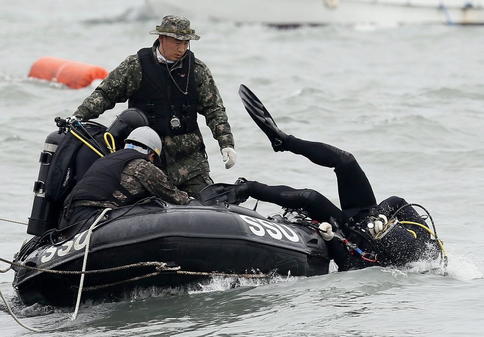 Potápěč se právě ponořuje do vody, aby pátral po dalších obětech tragédie.