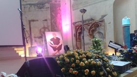 Pódium kostela zdobí smuteční věnce, květiny a fotka Jana Kaplického