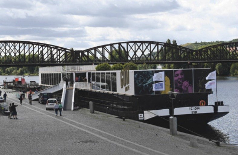 Loď BigMedia kotví u železničního mostu na Rašínově nábřeží.