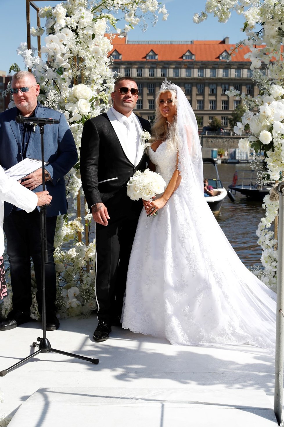 Honosné svatební šaty Lely Vémolové a sváteční smoking Karlose s bílými lampasy na kalhotách.