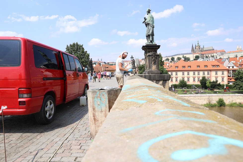 Odstraňování graffiti k Karlova mostu, který letos v červenci posprejovala dvojice mladých lidí. (15. července 2021)