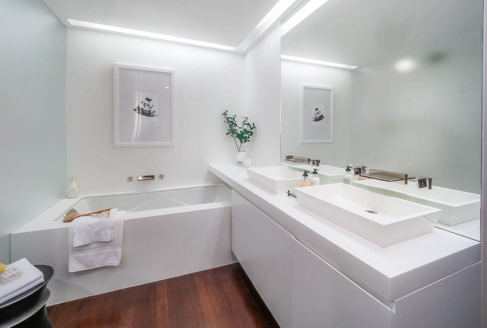 Bílá barva kontrastuje s dřevěnými podlahami v koupelně.