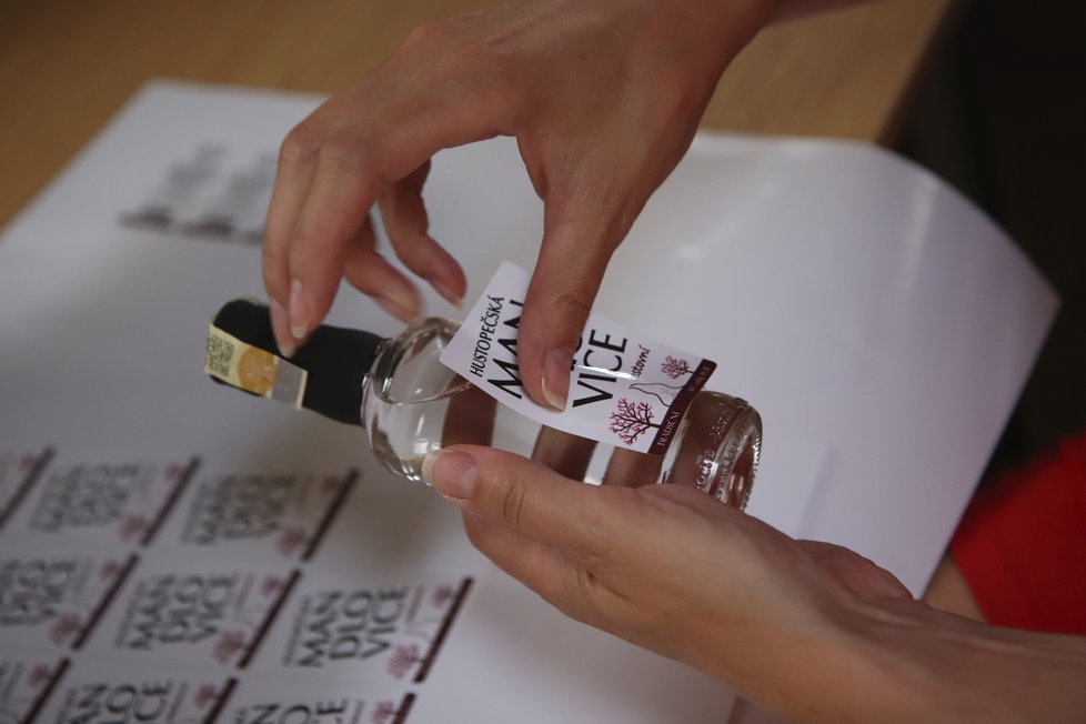 Lucie Krejčíříková (43) lepí etikety na láhve mandlovice o objemu 0,2 litru.