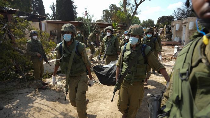 Izraelští vojáci odnášejí oběti sobotního útoku Hamásu na kibuc Kfar Azza