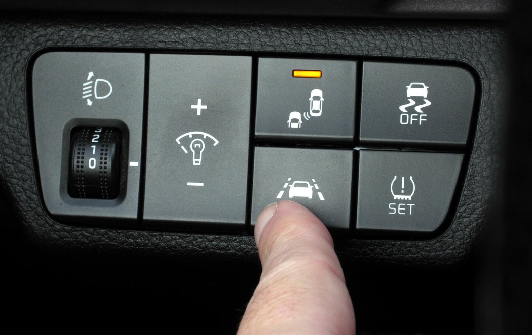 Tahle dvě tlačítka nad prstem mají hodnotu celých dvou hvězdiček v nárazovém testu Euro NCAP, a tak si jich adekvátně považujte… Patří k příplatkovému balíku jízdních asistentů, dříve nazývanému ADAS. Obsahuje radarový systém nouzového brzdění (AEB), hlídání jízdy v pruhu (LWDS, defaultně zapnuto), sledování únavy řidiče (DAW) a u vyšších výbav i praktické hlídání mrtvého úhlu zrcátek (BSD).