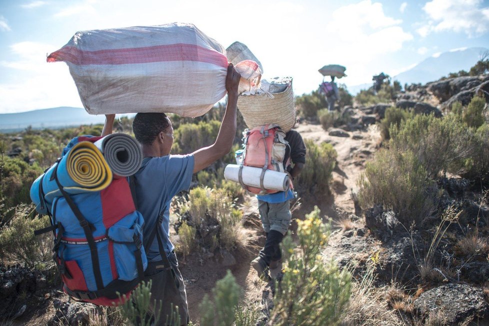 Při výstupu na Kilimandžáro turistům asistují průvodci, nosiči a kuchaři.