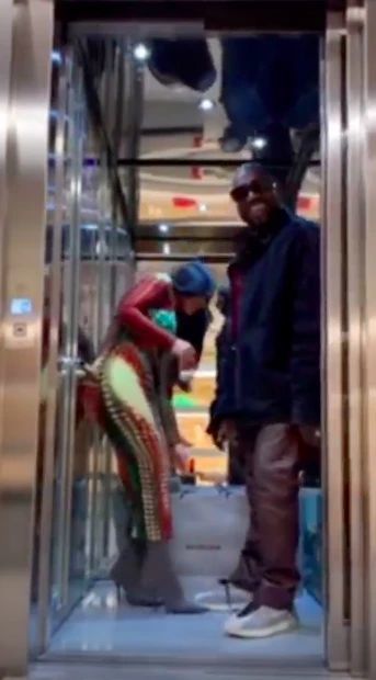 Dveře výtahu se otevírají, Kanye West vystupuje a nestará se o to, že jeho žena má kolem sebe několik nákupních tašek.