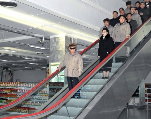 Kim Kjong-huj s Kim-Čong-ilem i Kim Čong-unem na eskalátoru