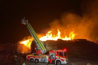 U Kladna hoří uskladněné dřevo: Na místě je přes 100 hasičů, škoda je 18 milionů korun