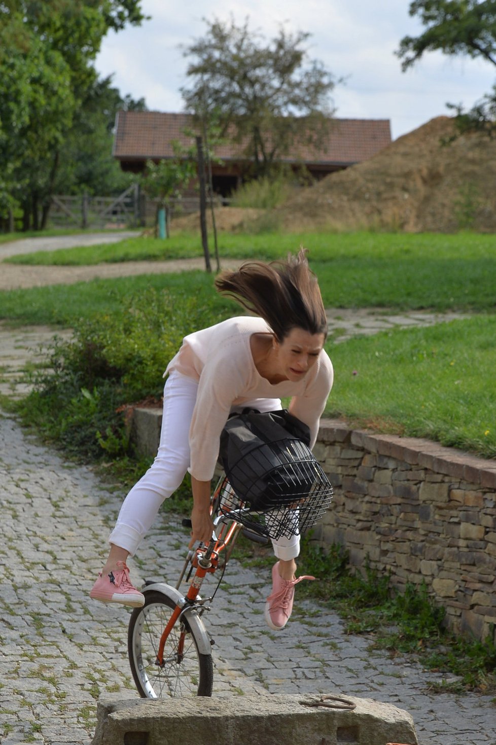 ﷯Klára Issová se coby Olga řítí na kole s nákupem v košíku.