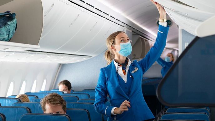 Aerolinky obrnily své posádky ochrannými štíty, rouškami či rukavicemi a některé měří cestujícím teplotu před letem. Na snímku je letuška společnosti KLM.