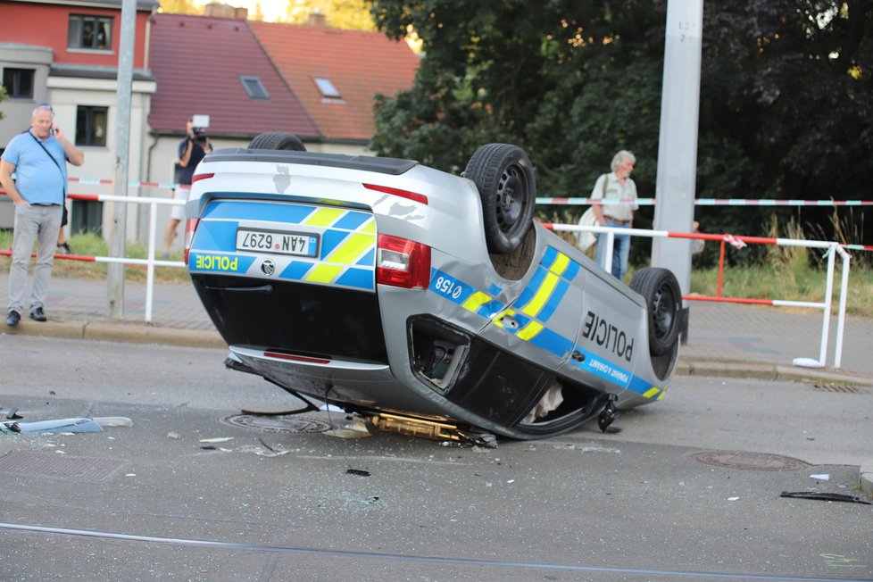 Nehoda v pražských Kobylisích: Policisté skončili s autem na střeše.