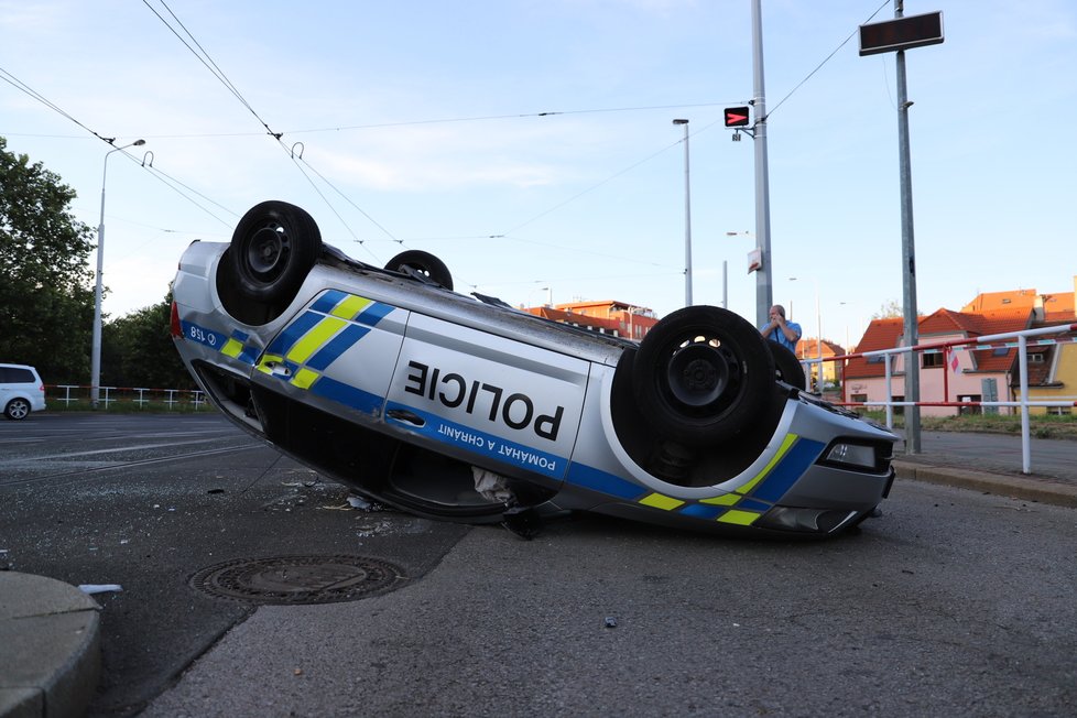 Nehoda v pražských Kobylisích: Policisté skončili s autem na střeše.