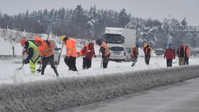 Dělníci odklízejí 16. prosince 2018 sníh na 96. kilometru v opravovaném úseku dálnice D1 s uzavřenými levými pruhy mezi Humpolcem a Větrným Jeníkovem. Ředitelství silnic a dálnic (ŘSD) poslalo firmě Geosan Group příkaz rozšířit jízdní pruhy (16. 12. 2018)