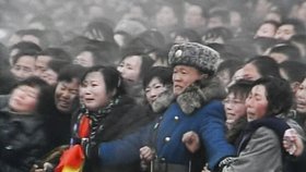 Voják se snaží zadržet plačící dav při pohřbu Kim Čong-ila