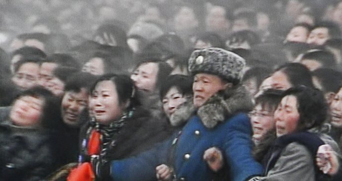 Voják se snaží zadržet plačící dav při pohřbu Kim Čong-ila