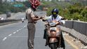 Policista nosí helmu představující koronavirus a žádá projíždějící, aby zůstali doma. Chennai, Indie.