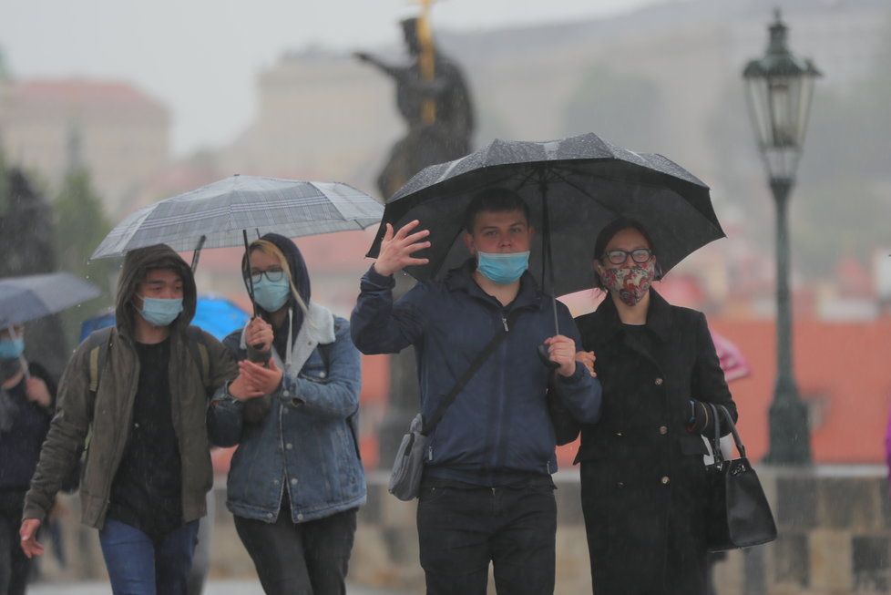 Lidé s deštníky na Karlově mostě v Praze