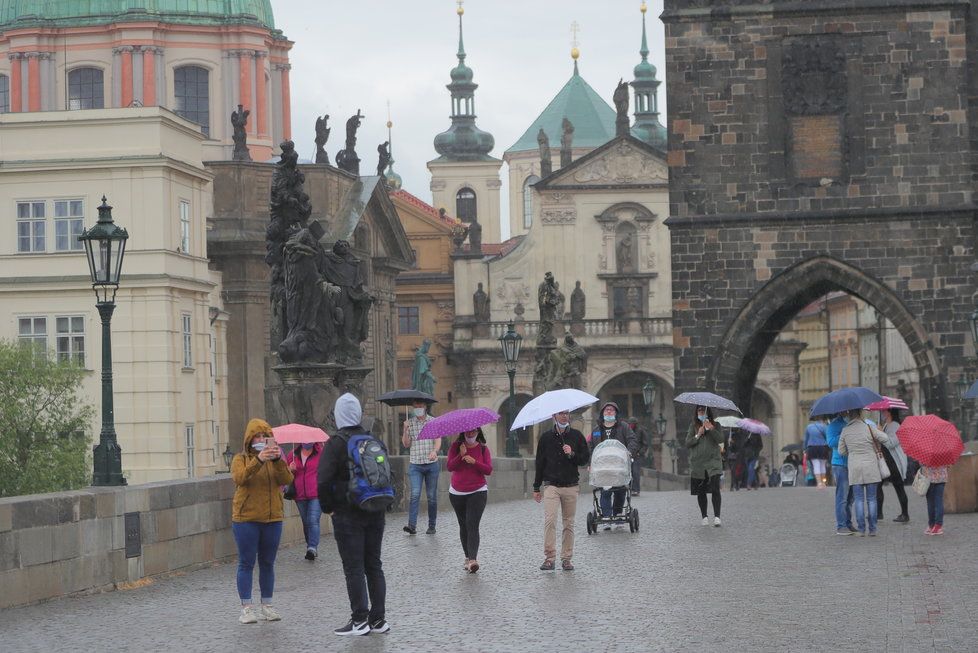 Lidé s deštníky na Karlově mostě v Praze