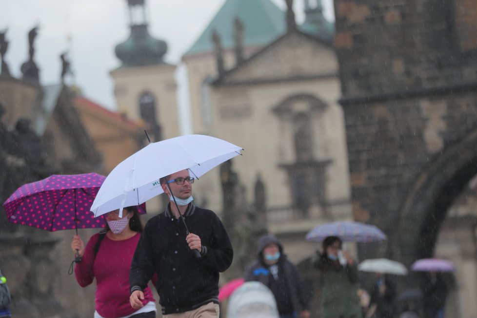 Lidé s deštníky na Karlově mostě v Praze