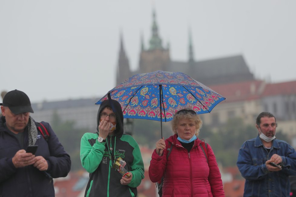 Lidé s deštníky na Karlově mostě v Praze