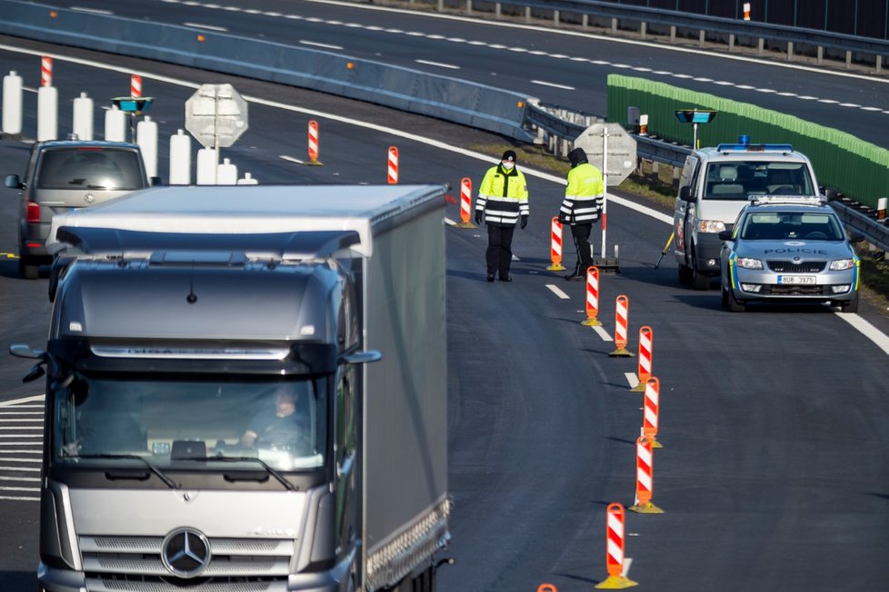 Kamion projíždí kolem kontrolního stanoviště na příjezdu z Německa na dálnici D8 před tunely Panenská u Petrovic na Ústecku poblíž česko-německého hraničního přechodu Petrovice/Lückendorf, jehož provoz byl 16. března 2020 omezen kvůli hrozbě koronaviru (16. 3. 2020)