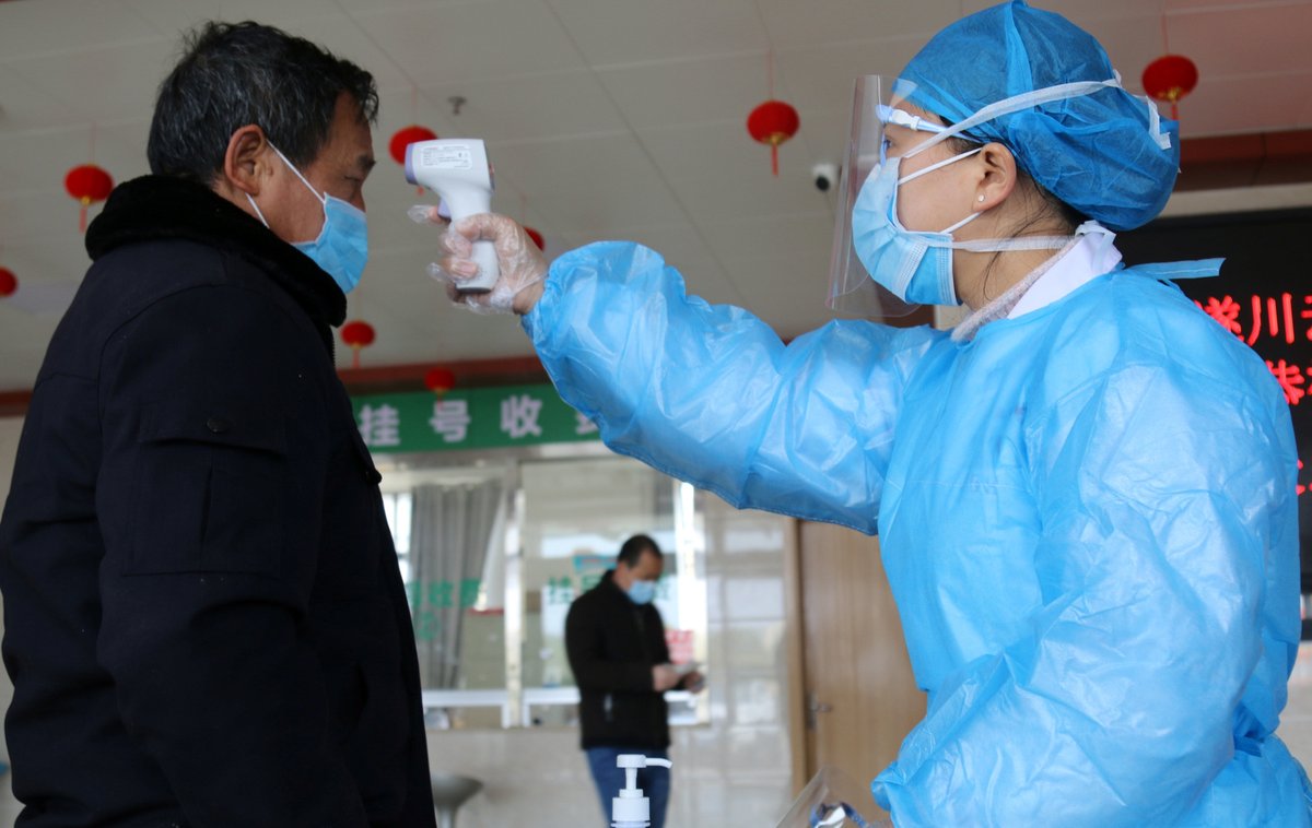 Kvůli epidemii koronaviru platí přísná bezpečnostní opatření jako měření teploty nebo rouška, snímek z čínského Wu-chanu, ohniska nákazy.