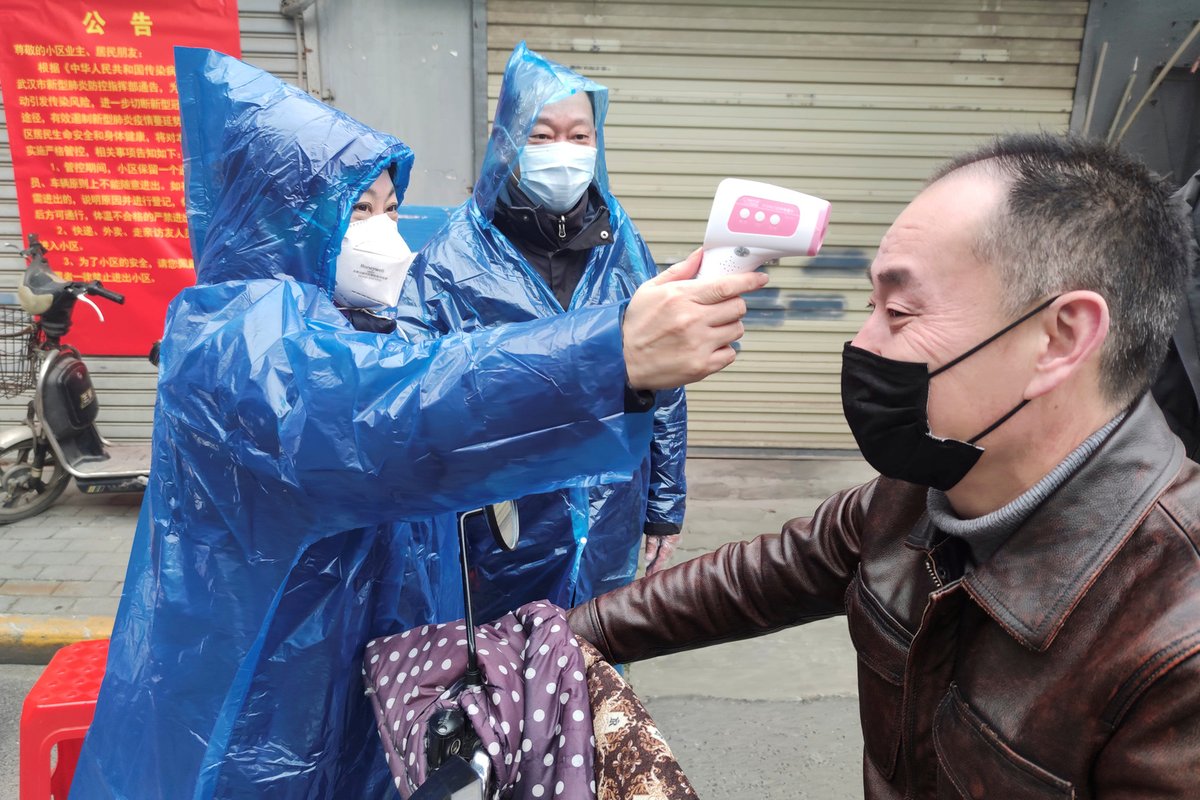 Kvůli epidemii koronaviru platí přísná bezpečnostní opatření jako měření teploty nebo rouška, snímek z čínského Wu-chanu, ohniska nákazy.