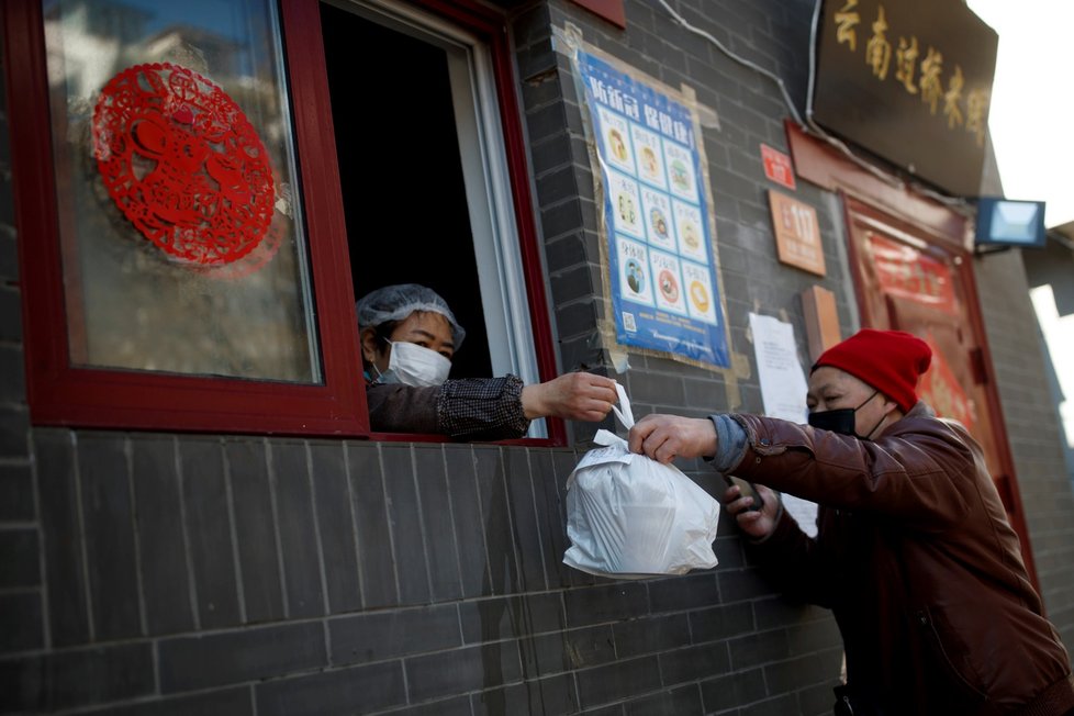 Muž v Pekingu si vyzvedává jídlo v restauraci (3. 3. 2020).