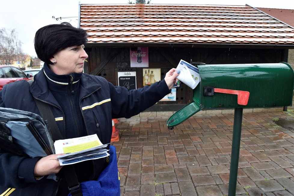 Doručovatelka pošty roznáší lidem do schránek letáky s informacemi o koronaviru. (11.3.2020)