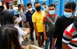 Lidé v Bangladéši stojí ve frontě na ochranné masky a měření teploty.