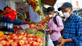 Lidé v Bangladéši nakupují potraviny v ochranných maskách.
