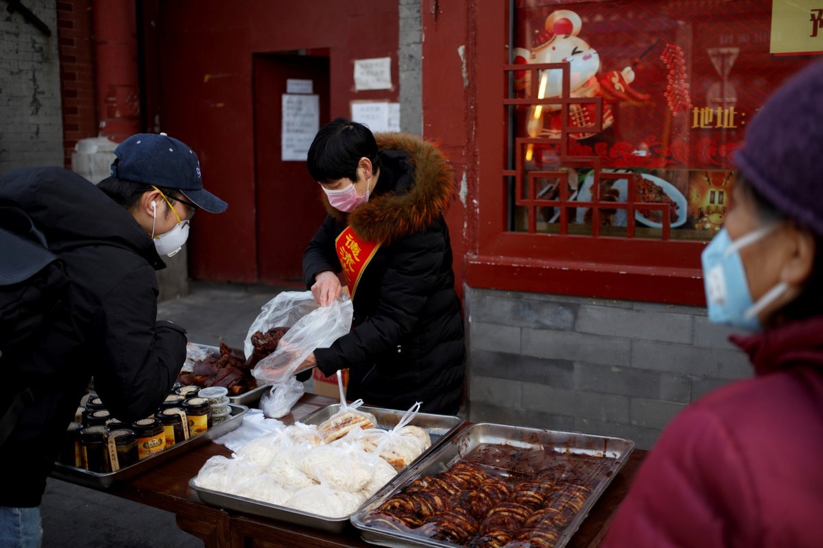 Lidé nakupují jídlo v ochranných maskách v ulicích Pekingu